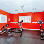 Fitness center in Village Springs Apartments featuring exercise equipment in a vibrant red room.