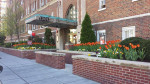 Entrance of Miramar apartments in Washington, DC, featuring colorful flower beds and historic architecture.