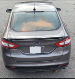 Rear view of a 2013 Ford Fusion Titanium Hybrid sedan in gray with sunroof and sleek design.