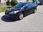 Black Kia Forte parked on the street, showcasing low mileage and good condition.