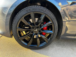 Close-up of black alloy wheel with red brake caliper on 2020 Tesla Model S at a driveway