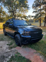 2007 black Avalanche SUV, perfect for trade or sale, parked outdoors among trees