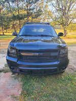 Front view of a black 2007 Avalanche with a mean look, parked in a grassy area.