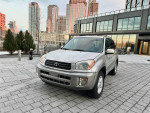 2001 Toyota RAV4 L AWD SUV in silver, parked in a modern urban area with tall buildings.