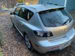 2007 Mazda 3 i Sport hatchback parked in driveway, showing rear view and silver color.
