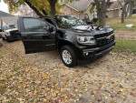 2021 Chevrolet Colorado LT 4WD parked on a leaf-covered driveway, showcasing its sleek black exterior.
