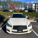 White Infiniti Q50 parked in a lot, featuring a sleek design and modern grille.
