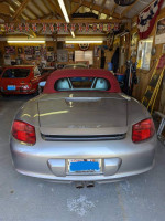 Rear view of a 2008 Porsche Boxster RS 60 Spyder in silver with red convertible top in a garage.