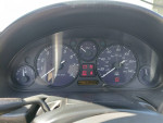 Dashboard of a 1999 Mazda MX-5 Miata showing speedometer and tachometer at 115k miles