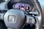 Close-up of the steering wheel and dashboard in a 2024 Honda Civic Sport, showcasing controls and display.