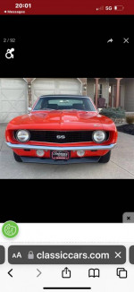 Front view of a 1969 Chevrolet Camaro SS in Hugger orange with black stripes, showcasing its classic design.