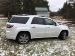 2016 GMC Acadia Denali FWD parked in snowy field, showcasing its sleek design and spacious body features.