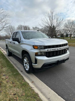 2019 Chevrolet Silverado 1500 in silver color parked by the road, showcasing its 4x4 capabilities.