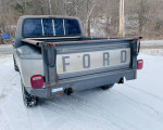 Rear view of a 1985 Ford F150 stepside truck with snowy background and visible 'FORD' tailgate