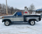 1985 Ford F150 stepside truck parked on snow with rural background, showcasing vintage design and solid condition.