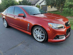 2015 Chevrolet SS in red color, showcasing stylish design and sporty wheels, parked in a residential area.