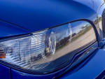 Close-up of the headlight of a 2005 BMW e46 330ci Convertible in Mystic Blue, showcasing its restored condition.