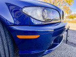 Close-up of a restored 2005 BMW 330ci Convertible in Mystic Blue, showcasing the front bumper and headlights.