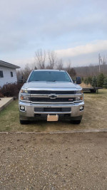 Front view of a 2015 Chevrolet Silverado 1500 LT in silver color, showcasing its robust design and large mirrors.