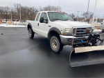 2002 Ford F250 plow truck 4x4 in good condition with a Western ultramount plow, parked on a snowy surface.