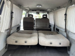 Interior view of a 1995 Nissan Homy van with flexible seating and curtains, ideal for camping adventures.