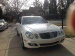2007 Mercedes Benz E350 4-Matic sedan in white parked in a driveway with trees in the background.