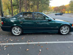 1997 BMW M3 E36 sedan in green with grey leather interior, parked outdoors with autumn leaves