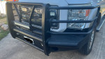 Close-up of a Ford F250 front bumper with steel grille and off-road lights, showcasing its robust design.