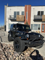2007 Jeep Wrangler Rubicon 4WD in black, showcasing upgrades and off-road tires outside a modern building.