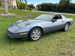 1990 Chevrolet Corvette in Steel Blue Metallic parked on grass, showcasing its classic design and well-maintained condition.