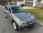 2014 BMW X3 xDrive28i AWD parked on a residential street, showcasing its sleek gray exterior.