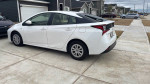 Side view of a 2021 Toyota Prius parked in a residential area, showcasing its sleek design and eco-friendly features.