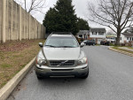2008 Volvo XC90 in gray color, parked on a residential street, showing some dings and rear damage.
