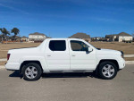 2010 Honda Ridgeline 4WD parked on a residential street, showcasing its white exterior and clean lines.