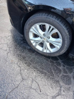 Close-up of a 2015 Chevrolet Impala's alloy wheel and tire on wet pavement.