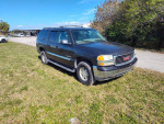 2006 GMC Yukon XL K1500 in black, parked on grass, showcasing its rugged design and spacious interior.