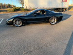Black Chevrolet Corvette with aftermarket wheels and performance upgrades parked on a sunny day