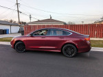 2015 Chrysler 200 Limited in maroon color parked on the street, showcasing its sleek design and black alloy wheels.