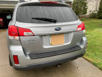Rear view of a silver 2011 Subaru Outback 2.5i AWD, parked with rain on the windows.