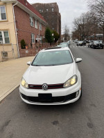 Front view of a 2011 Volkswagen GTI in white, showcasing its sleek design and sporty features.