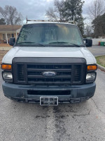 Front view of a 2008 Ford E-150 cargo van with ladder racks and storage bins for sale.