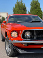 Close-up of a 1969 Ford Mustang Mach 1 in Calypso Coral color, showcasing classic American automotive design.