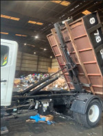 2007 Hino 268 truck with Swap Loader lifting a dumpster in a warehouse, ideal for waste management tasks.