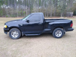 1998 Ford F-150 XLT 4WD in black, parked on grass, showing side profile in good condition.