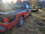 1999 Dodge Dakota truck with scratches parked on grass, featuring dependable performance and well-maintained interior.