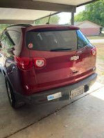 Rear view of a 2011 Chevrolet Traverse LS in burgundy color parked under a shelter.
