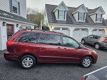 2010 Toyota Sienna LE minivan in excellent condition, parked in a driveway with other cars.