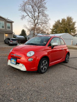 2014 red FIAT 500e parked on a street, showcasing its compact design and electric features, perfect for city driving.