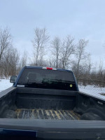 Rear view of a 2019 F-250 Superduty truck bed on a snowy day, showcasing bed liner and plow mount.