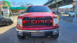 Front view of a red 2011 Ford F-150 Lariat 4WD, showcasing the bold grille and chrome accents.